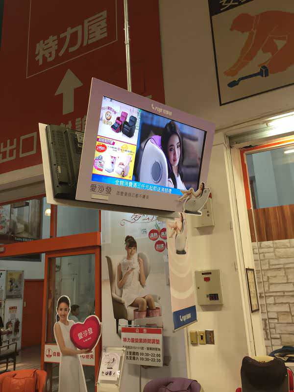 在大型生活用品卖场里的知名连锁健身按摩器材店，吊挂广告机与电视